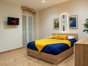 Ein modernes Schlafzimmer mit einem hölzernen Bett, einem Fernseher und zwei gerahmten Bildern an der Wand.