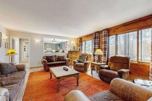 A living room with a sofa, armchairs, a coffee table, and a fireplace. There is a kitchen in the background. - Waterfront, dog-friendly home with dock, kayaks, NEW hot tub, game room, & AC (Eagle River)
