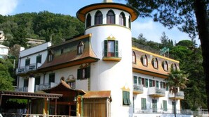 A multi-story building with a tower-like structure, balconies, and a covered area with a roof. - Hotel Residence Moneglia (Moneglia)