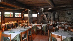 A restaurant with wooden beams, stone walls, and tables set for dining. - Hotel Residence Moneglia (Moneglia)