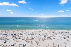 Ein voller Strand mit vielen Sonnenschirmen und Liegestühlen.