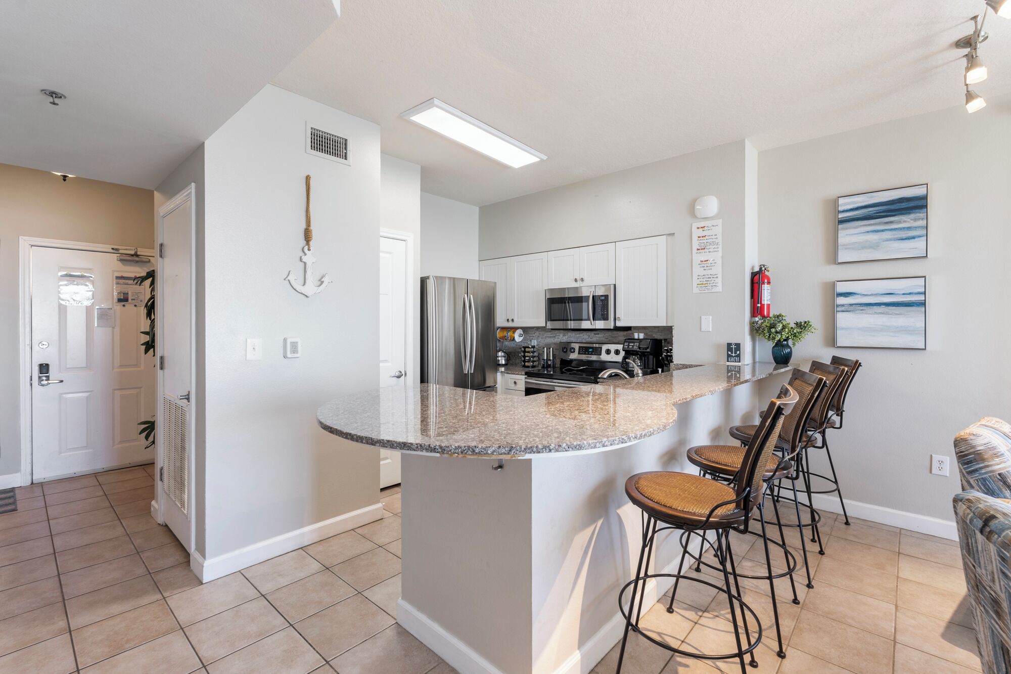 Een moderne keuken met een centraal eiland, roestvrijstalen apparatuur en barstoelen.