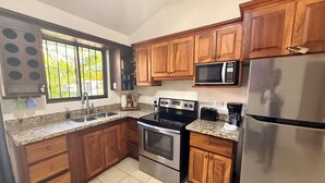 Una cocina con armarios de madera, un refrigerador de acero inoxidable, un microondas, una estufa y un lavamanos.