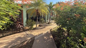 Un sendero bordeado por abundante vegetación y un edificio con balcón.