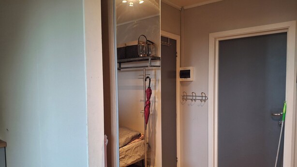 A room with a bed, a wardrobe, a mirror, and a door with a green handle.