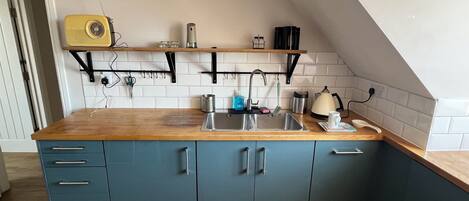 A kitchen with a wooden countertop, a sink, and cabinets.