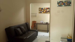 Uma sala de estar com um sofá preto, uma mesinha e um tapete estampado.