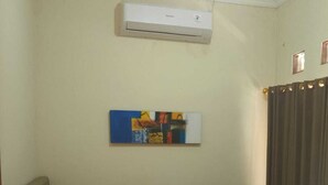 Quarto com uma cama, ar condicionado, um quadro e cortina.