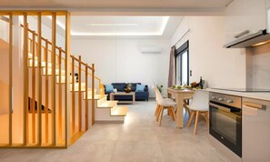 Une cuisine moderne avec un coin repas, un escalier et un salon comprenant un canapé et une table basse.