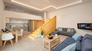 Ein zeitgemäßer Wohnraum mit Treppe, Essbereich, Sofa und Flachbildfernseher.