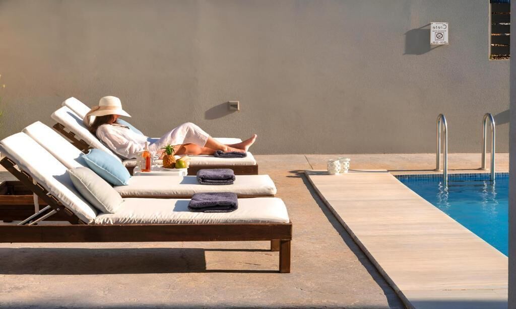 Ett område vid poolen med solstolar, en pool och en skylt som är monterad på väggen.