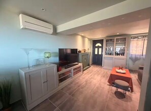 Ein Wohnzimmer mit Fernseher, Schrank und Essbereich mit Tisch und Stühlen.