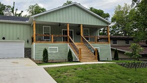 Une maison à deux étages avec un porche couvert, un garage à l’avant et un petit jardin devant.