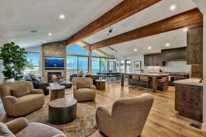 A spacious living area with a fireplace, comfortable seating, a kitchen with modern appliances, and large windows offering a mountain view.