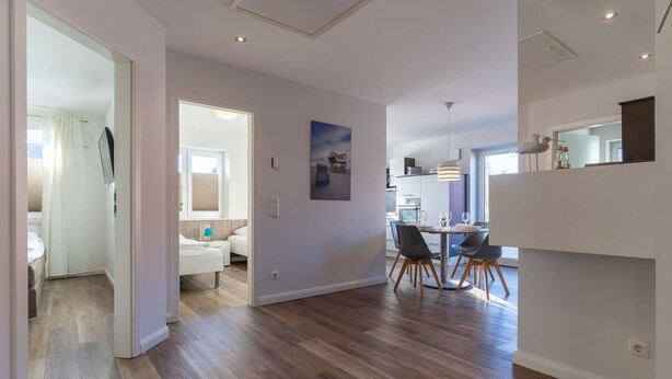 Ein modernes Interieur mit Essbereich, Küche und einem Schlafzimmer mit großem Fenster.