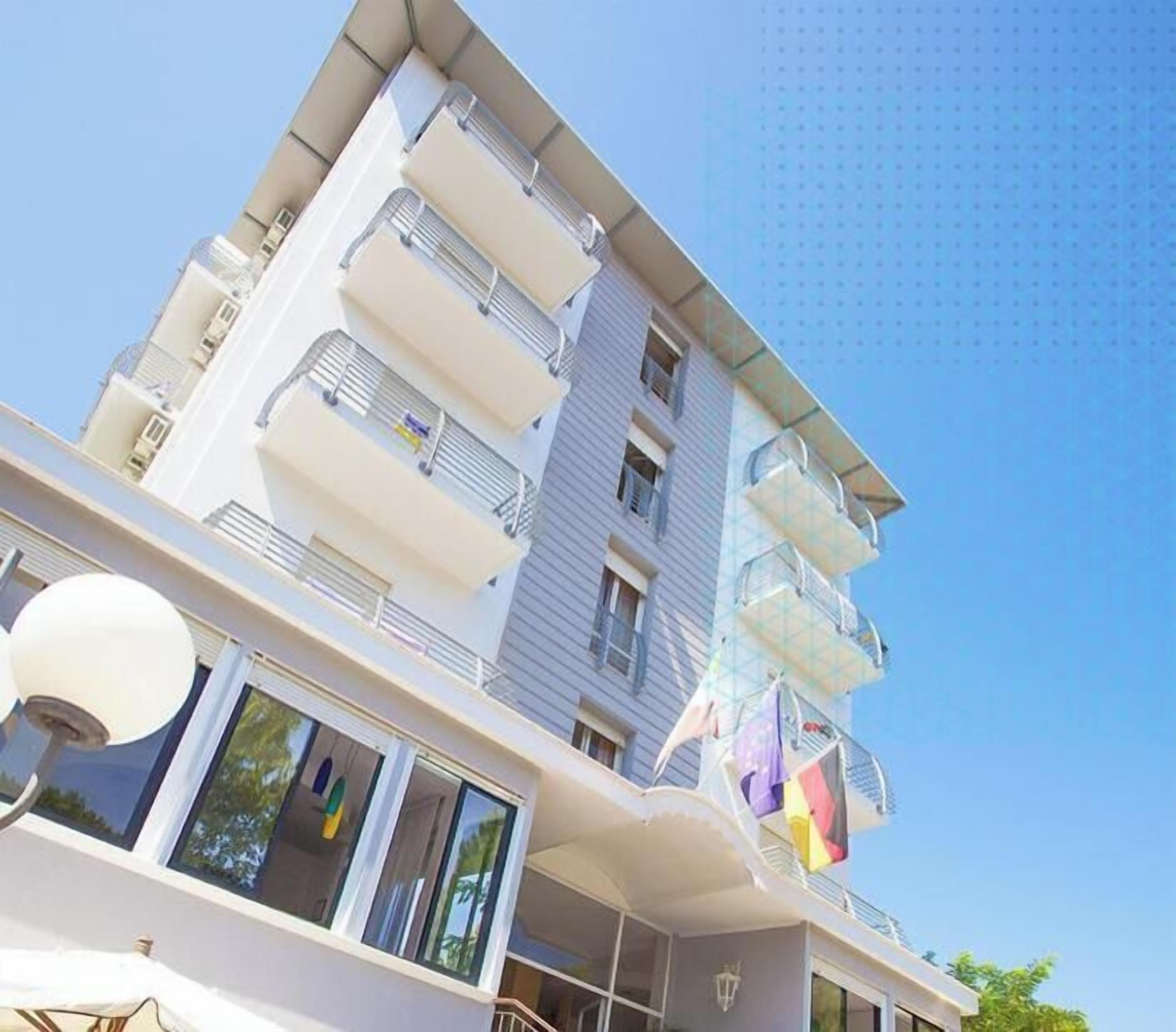 A multi-story building with balconies, large windows, and a clear sky.