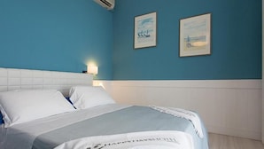 Une chambre d’hôtel avec un lit, une table de chevet et deux tableaux accrochés au mur.