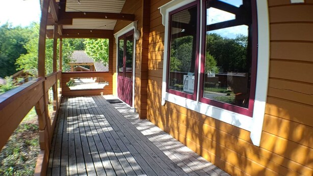 A wooden deck with a covered porch, large windows, and a visible house number 52.