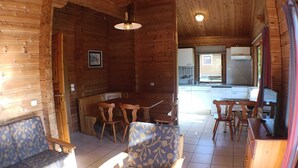 A wooden interior with a dining area, a kitchen, and a view of the outside.