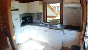 A compact kitchen with white cabinets, a built-in oven, a sink, and a dishwasher.