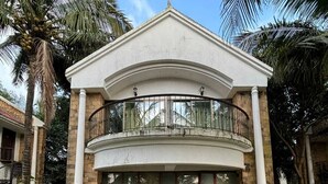 A two-story building with a balcony, surrounded by well-maintained gardens and palm trees. - Silverador Resort Club (Mira Bhayandar)