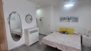 Quarto com cama, mesa de cabeceira, cômoda, espelho e ventilador de teto.