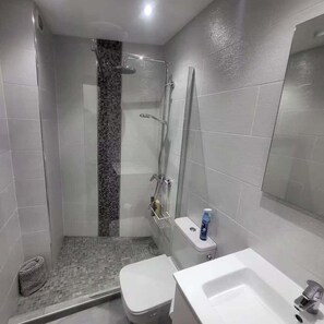 Ein Badezimmer mit Dusche, Toilette und Waschbecken.