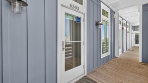 A corridor with a door labeled '6303' and a metal lantern on the wall. - Spacious 3 Bedroom Condo in Cinnamon Shore North Near Pools & Beach (Port Aransas)