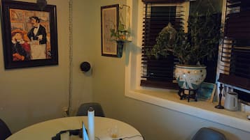 A dining area with a round table, a laptop, a candle, and a hanging light fixture.