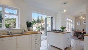 Een moderne keuken met witte kasten, een centraal eiland en een eethoek met een tafel en stoelen.