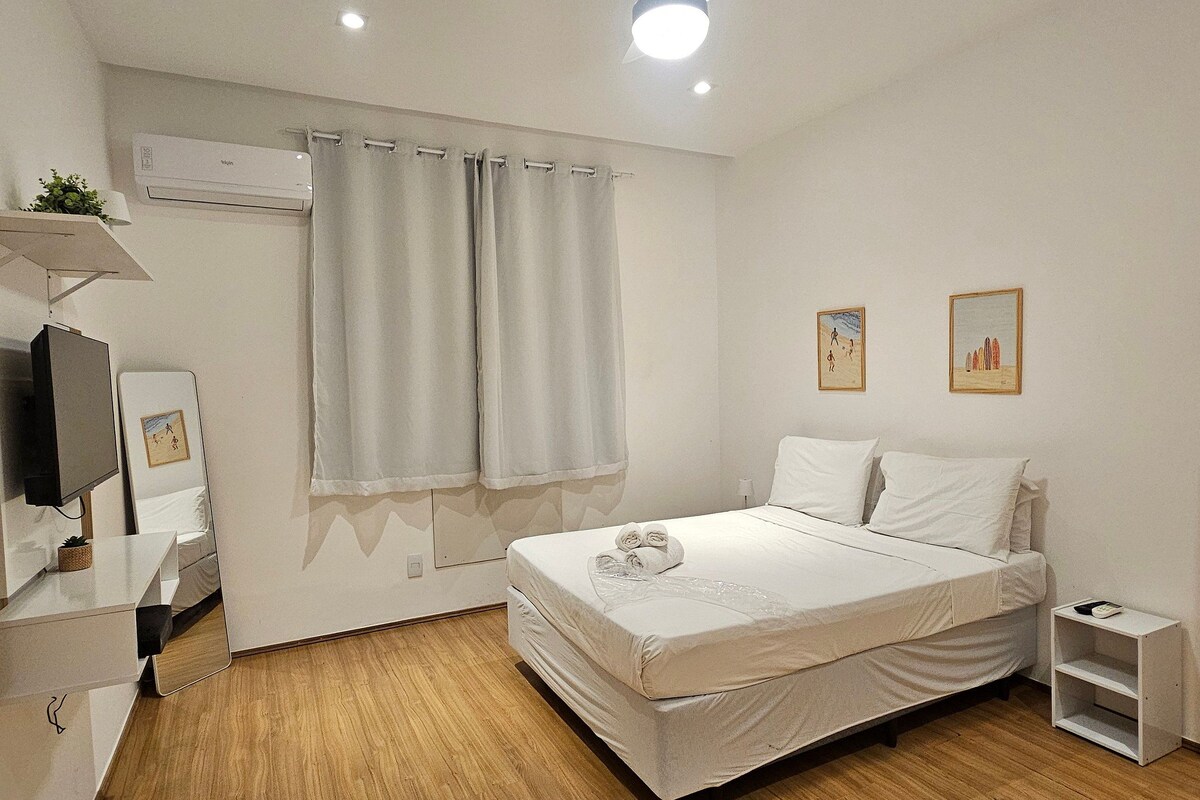 A bedroom with a bed, a television, a mirror, and a ceiling fan.