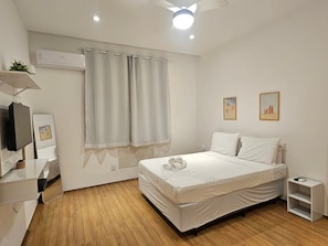A bedroom with a bed, a television, a mirror, and a ceiling fan. - Copacabana Breeze Studio, 5 minutes from the beach (Rio de Janeiro)