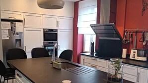 A modern kitchen with white cabinets, a black countertop, and a built-in oven. - Villa Bénédictins (Limoges)