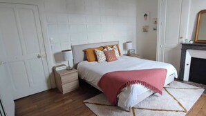 A bedroom with a bed, bedside table, lamp, and a fireplace. - Villa Bénédictins (Limoges)