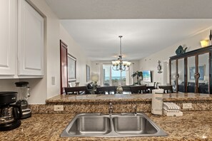 Eine Küche mit Granit Arbeitsplatten, Edelstahlspülen und einer Chandelüster.