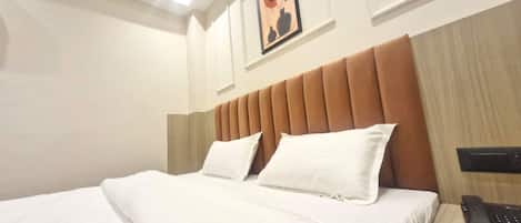 A hotel room with a bed, a telephone, and a painting on the wall.