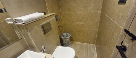 A small bathroom with a toilet, sink, and shower.