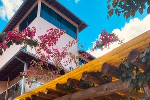 A building with a white facade and a balcony with pink flowers. - Pousada Chácara Santa Inês (Conceição do Mato Dentro)