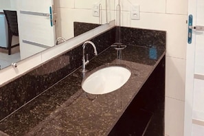 A bathroom with a marble sink, a mirror, and a towel rack. - Pousada Chácara Santa Inês (Conceição do Mato Dentro)