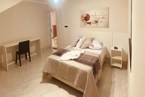 A bedroom with a bed, a desk, and a chair. There is a painting on the wall. - Pousada Chácara Santa Inês (Conceição do Mato Dentro)