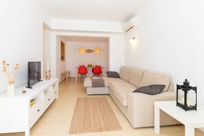 Ein modernes Wohnzimmer mit einer Couch, einem Fernseher und einem Essbereich mit roten Stühlen.