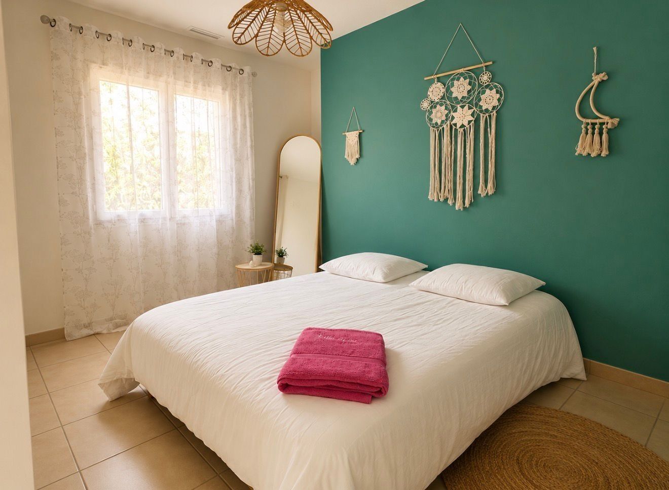 Een slaapkamer met een bed, een raam met gordijnen, een spiegel en decoraties aan de muur.