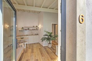 Una cocina moderna con suelo de madera, un área de comedor con mesa y sillas, una planta en maceta y el número 6 en la pared.