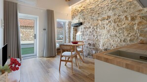Una cocina moderna con pared de piedra, piso de madera y comedor con mesa y sillas.