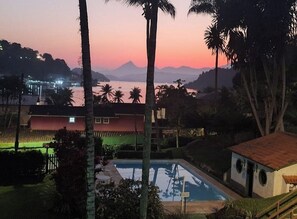 Área da piscina com vista para montanhas e pôr do sol.