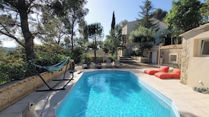Una piscina con sillas de descanso y una hamaca.