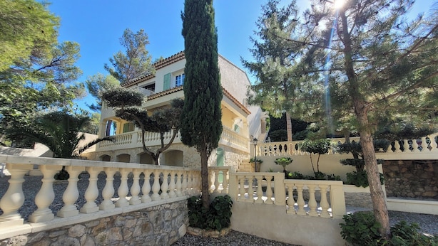 Un patio con muro de piedra, baranda decorativa y un edificio con tejado de tejas y balcones.