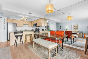 Eine moderne Küche mit Holzausstattung, Edelstahlgeräten und einem Essbereich mit einer Bank und orangefarbenen Stühlen.