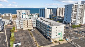 Ein mehrstöckiges Hotel mit Parkplatz, Blick auf das Meer und einer Straßenkreuzung.