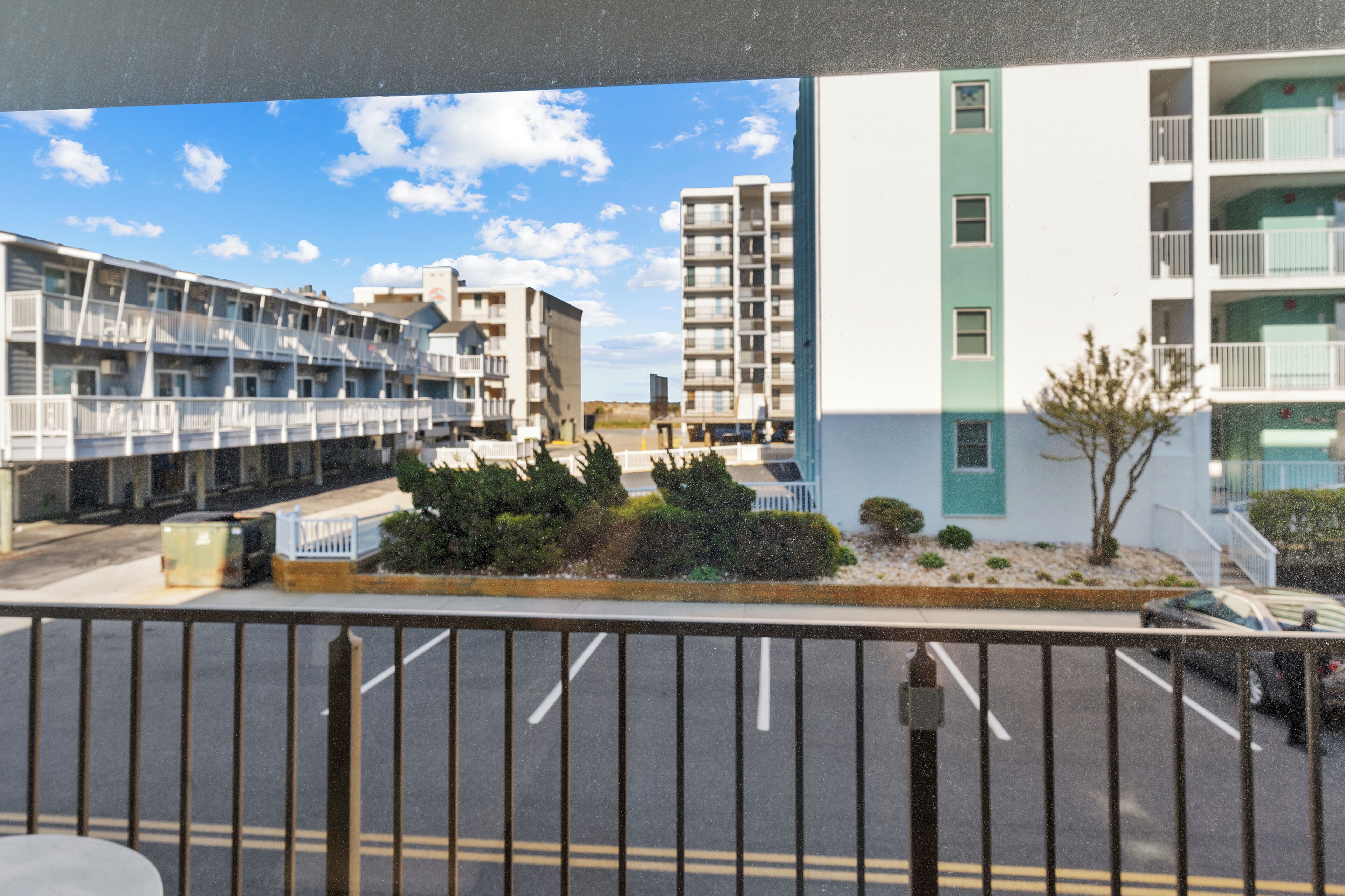 Un edificio de varios pisos con balcones, un estacionamiento y un cielo despejado.
